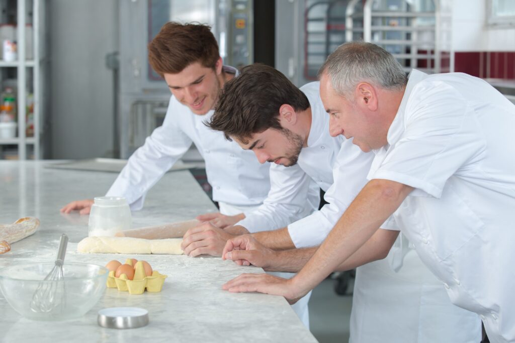 Un chef boulanger explique une technique à deux jeunes